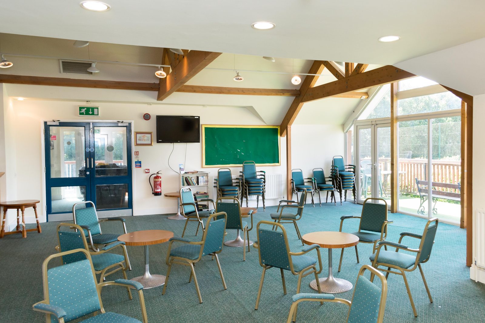 Inside the Memorial Pavilion function room, with vaulted oak-beamed ceiling, round tables, chairs and large windows looking out to the balcony